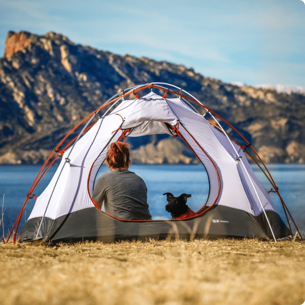 Traveller sitting in a tent beside a lake