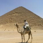 Camel rider in front of a pyramid in Egypt