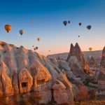 Hot air balloons over rock formations in Cappadocia at sunrise