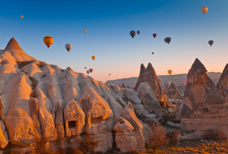 Hot air balloons over rock formations in Cappadocia at sunrise