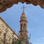 Church bell tower framed by a stone arch in southeastern Turkey